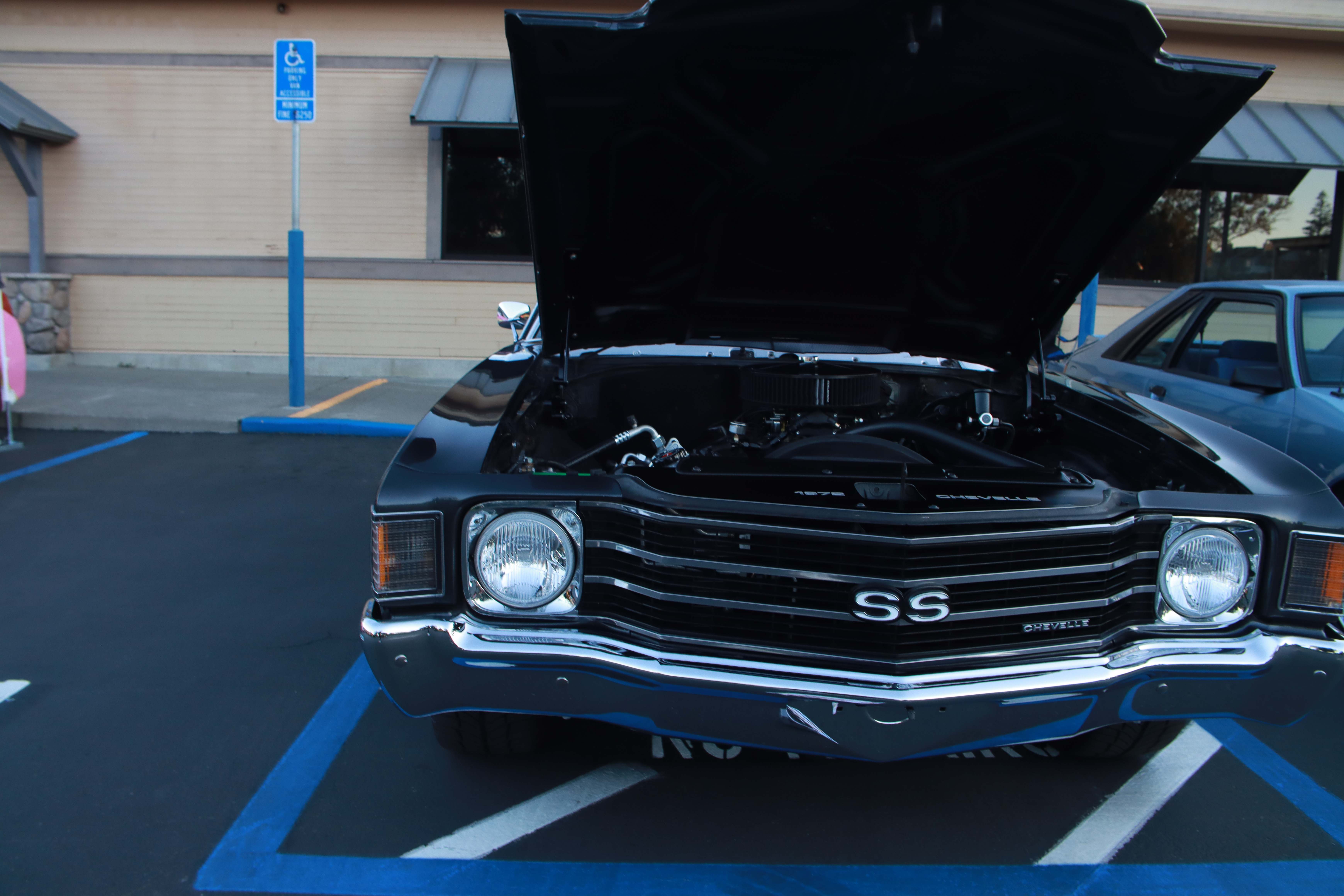 Yellow Mustang, light blue classic Mustang, and orange Dodge Challenger with hoods open
