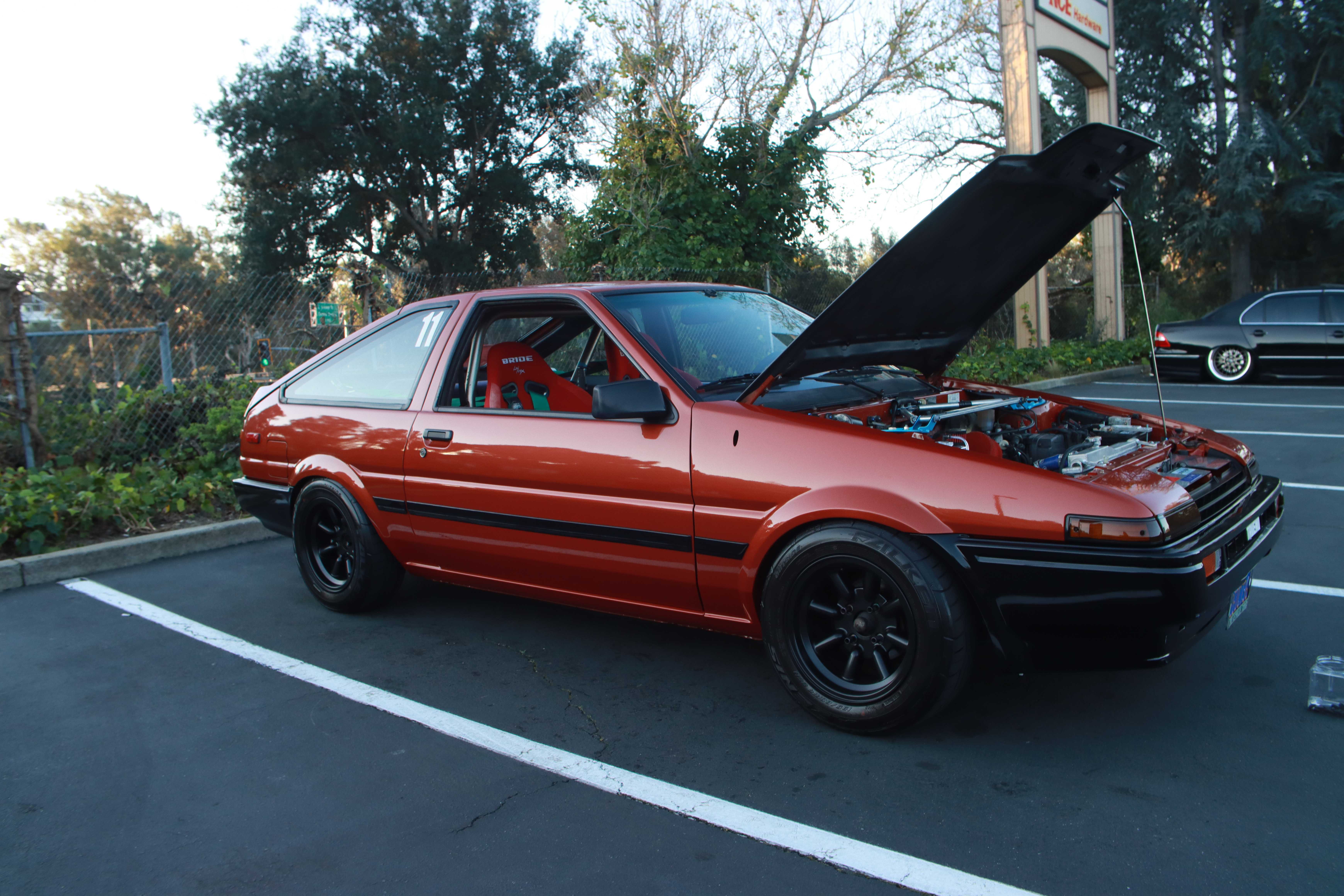 Red Toyota AE86 Corolla with hood open showing turbocharged engine