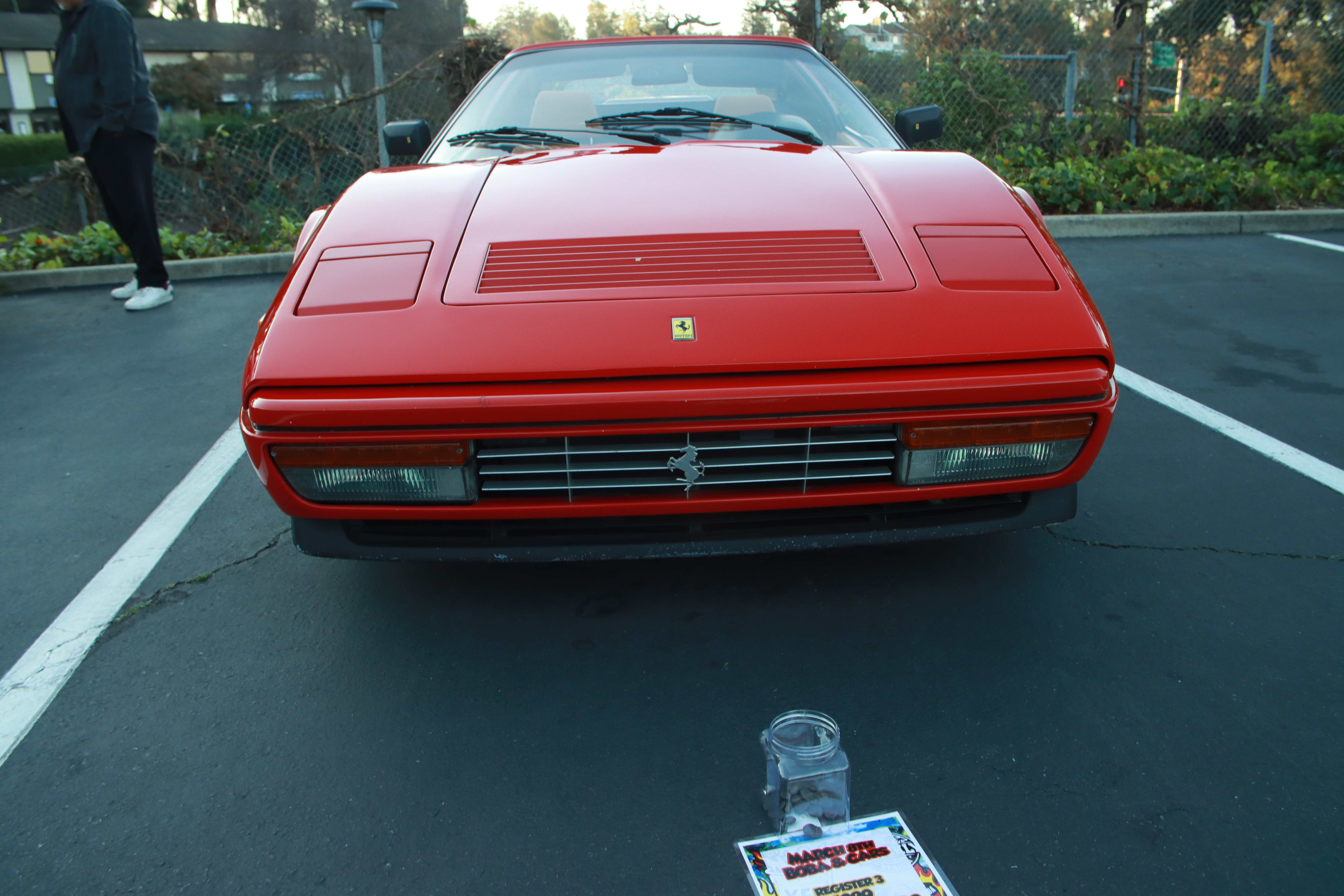 Ferrari 328 GTS head-on shot with community voting materials displayed