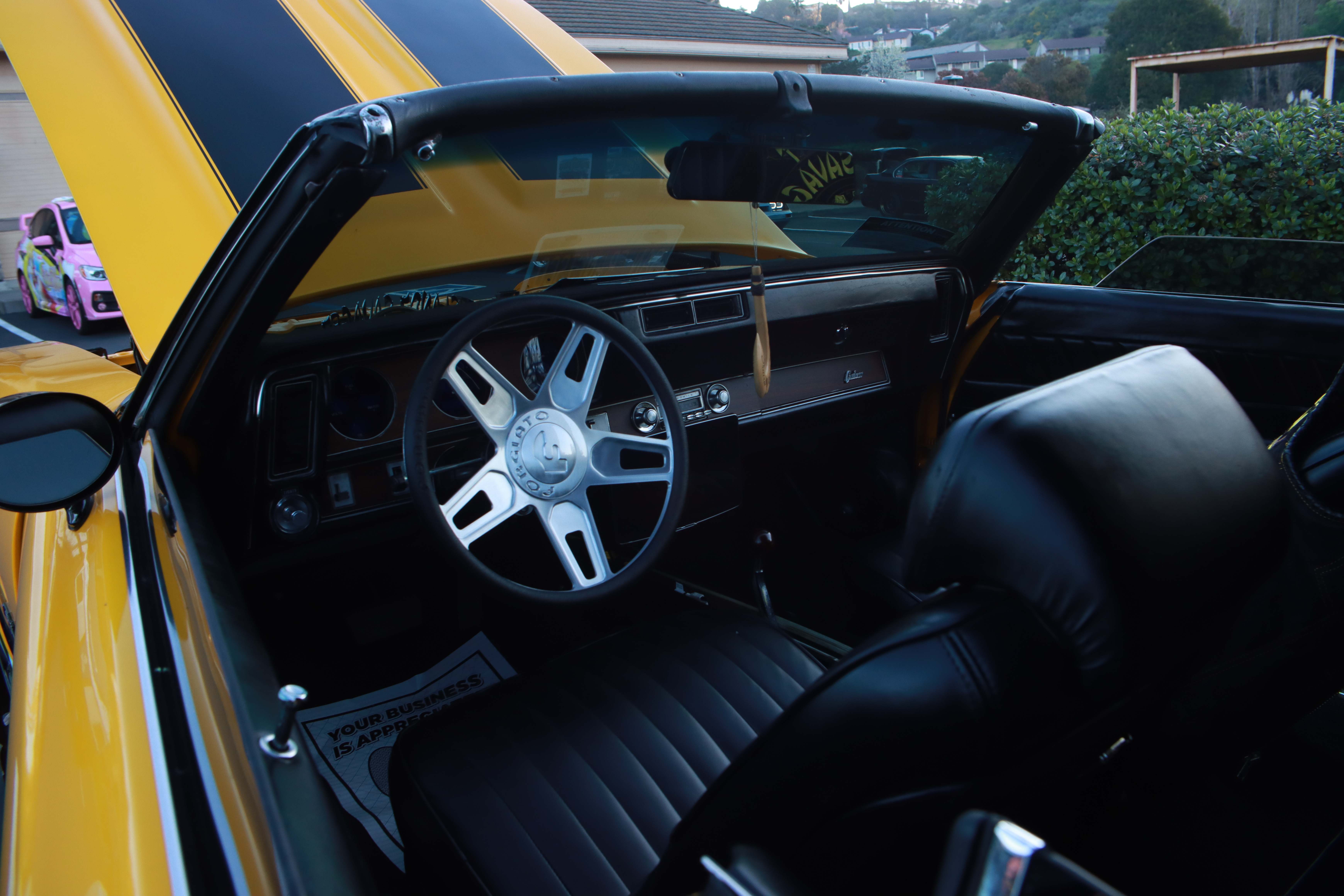 Orange Dodge Challenger with supercharged engine bay open near Raley's ACE Hardware